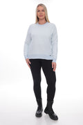 A woman modeling a light blue crewneck sweatshirt with black leggings and black combat boots, standing against a white studio background.