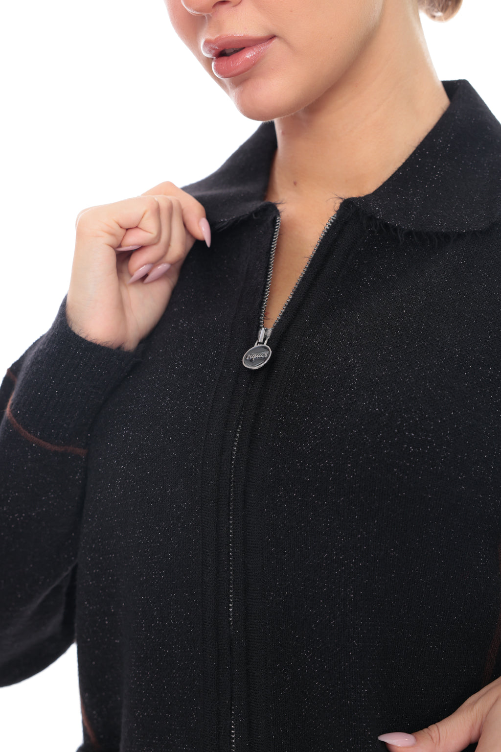 Close-up of a woman wearing a black zip-up jacket with a textured knit fabric, featuring a silver zipper and a small oval brand tag.