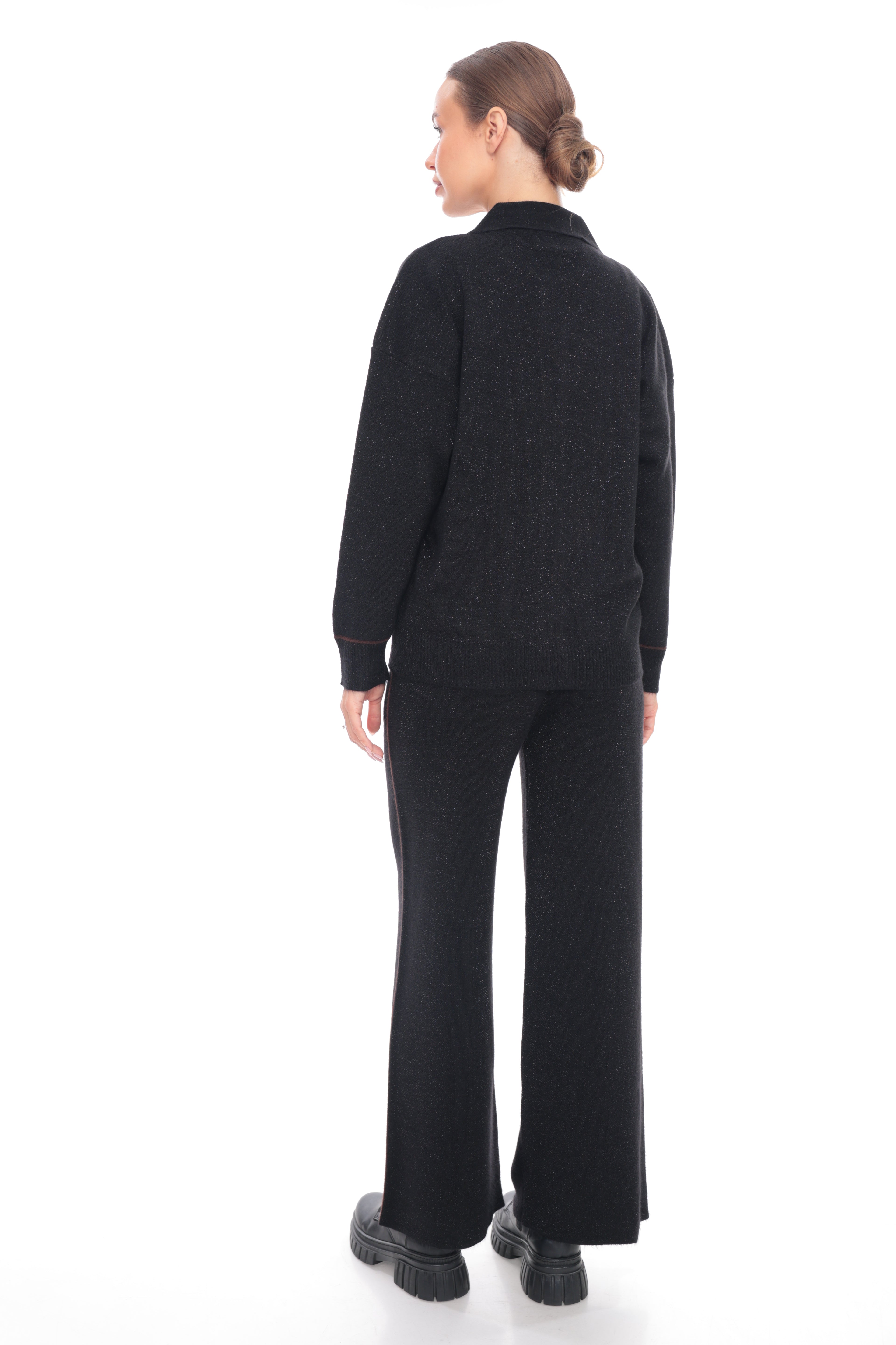 A model shown from the back wearing a black knit mock-neck sweater and matching wide-leg trousers against a plain white background.