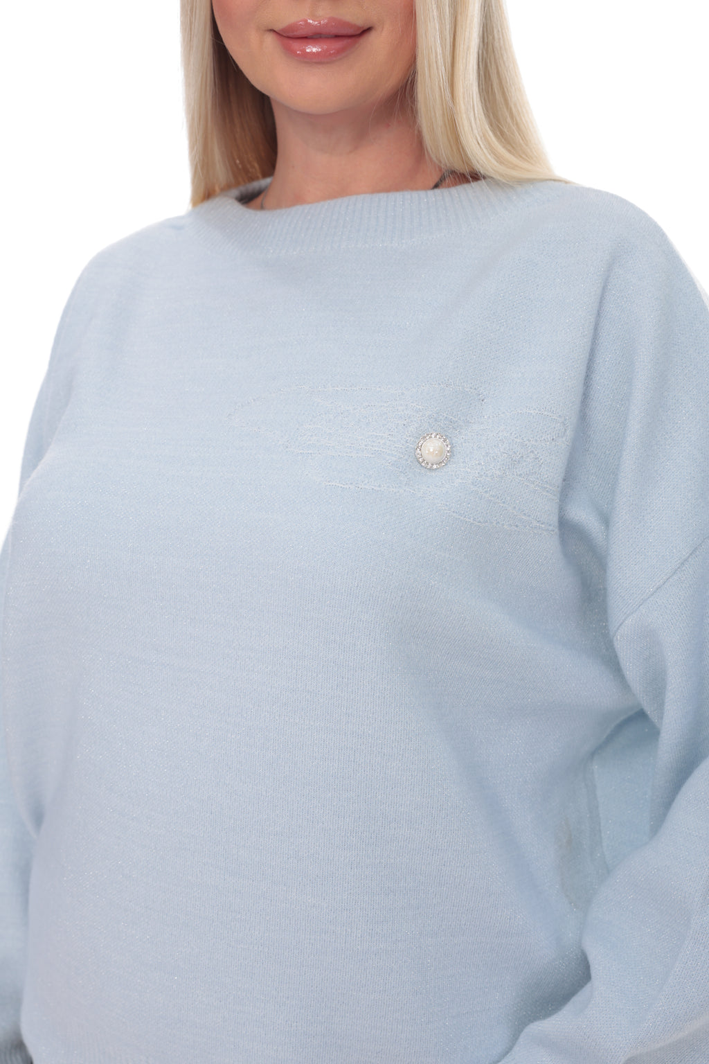 A close-up of a woman wearing a light blue knit sweater with a small pearl-like decorative accent on the chest, against a plain white background.