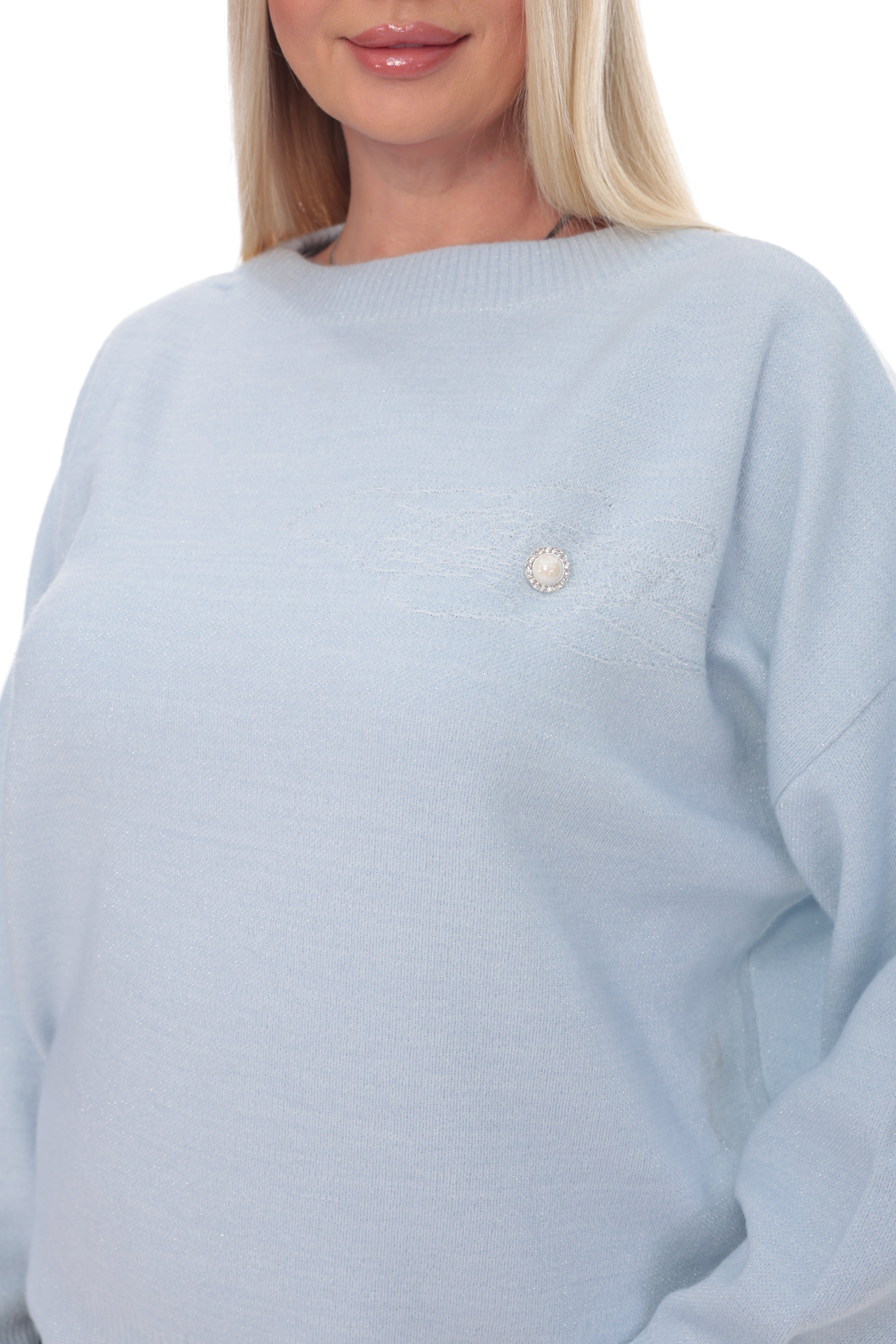 A close-up of a woman wearing a light blue knit sweater with a small pearl-like decorative accent on the chest, against a plain white background.