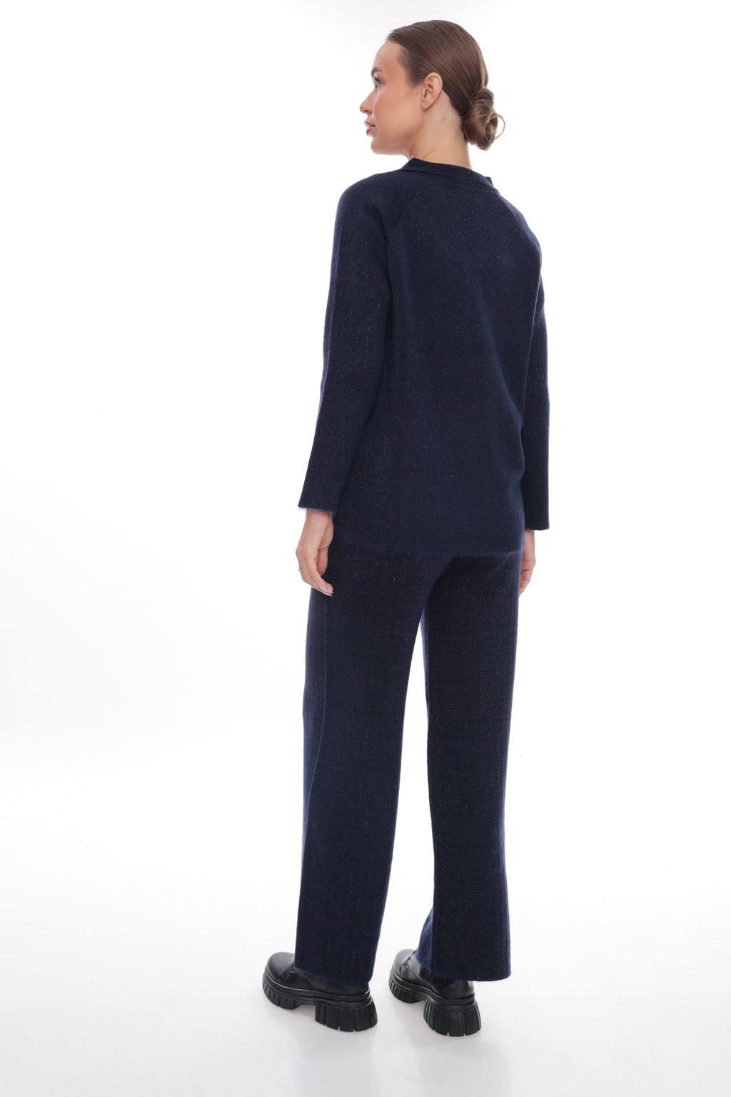 A model shown from the back wearing a matching navy blue knit sweater and wide-leg trousers set, paired with black platform shoes, against a solid white studio background.