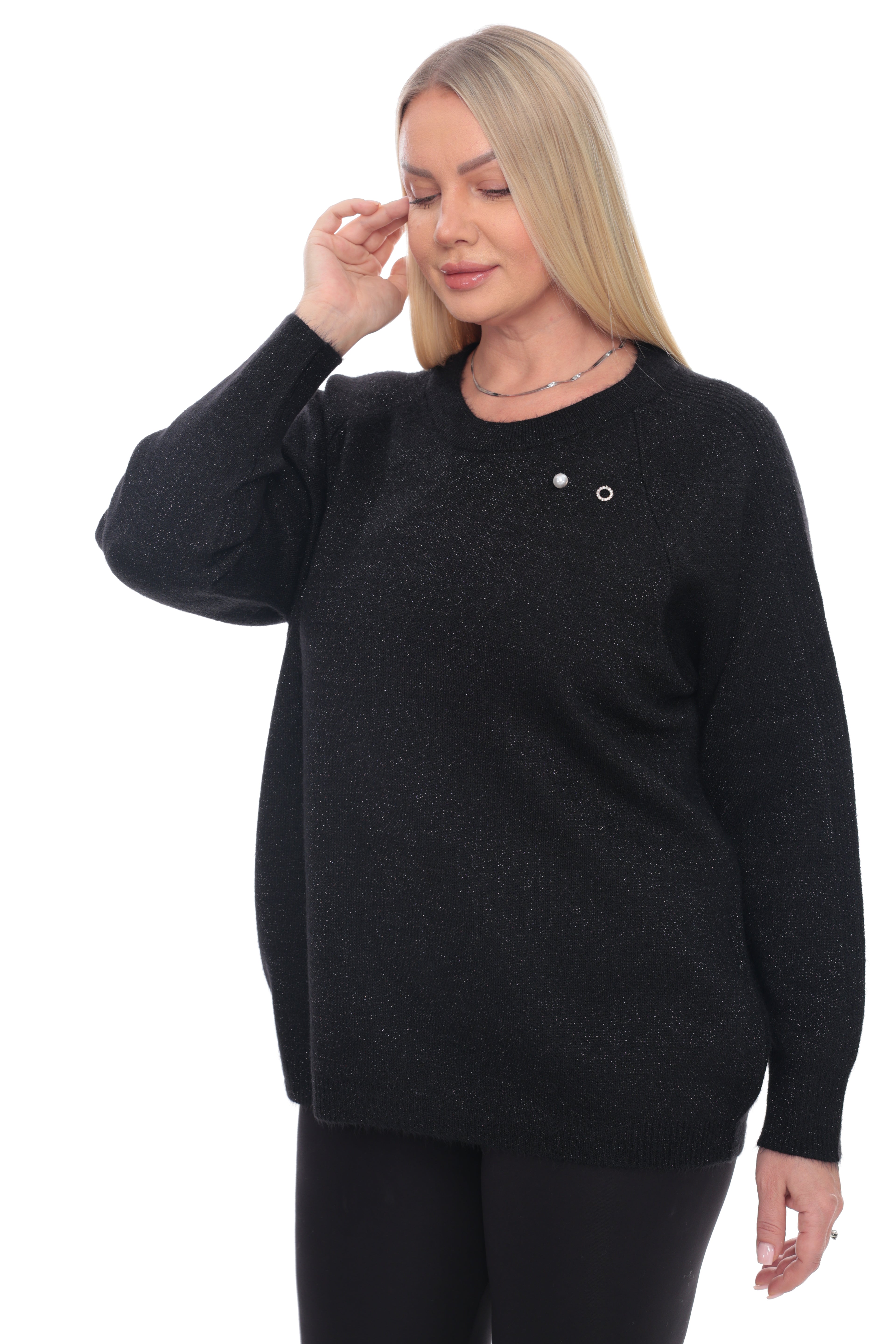 A woman modeling a black long-sleeve knit sweater with a small silver decorative detail on the chest, paired with black pants, against a plain white background.