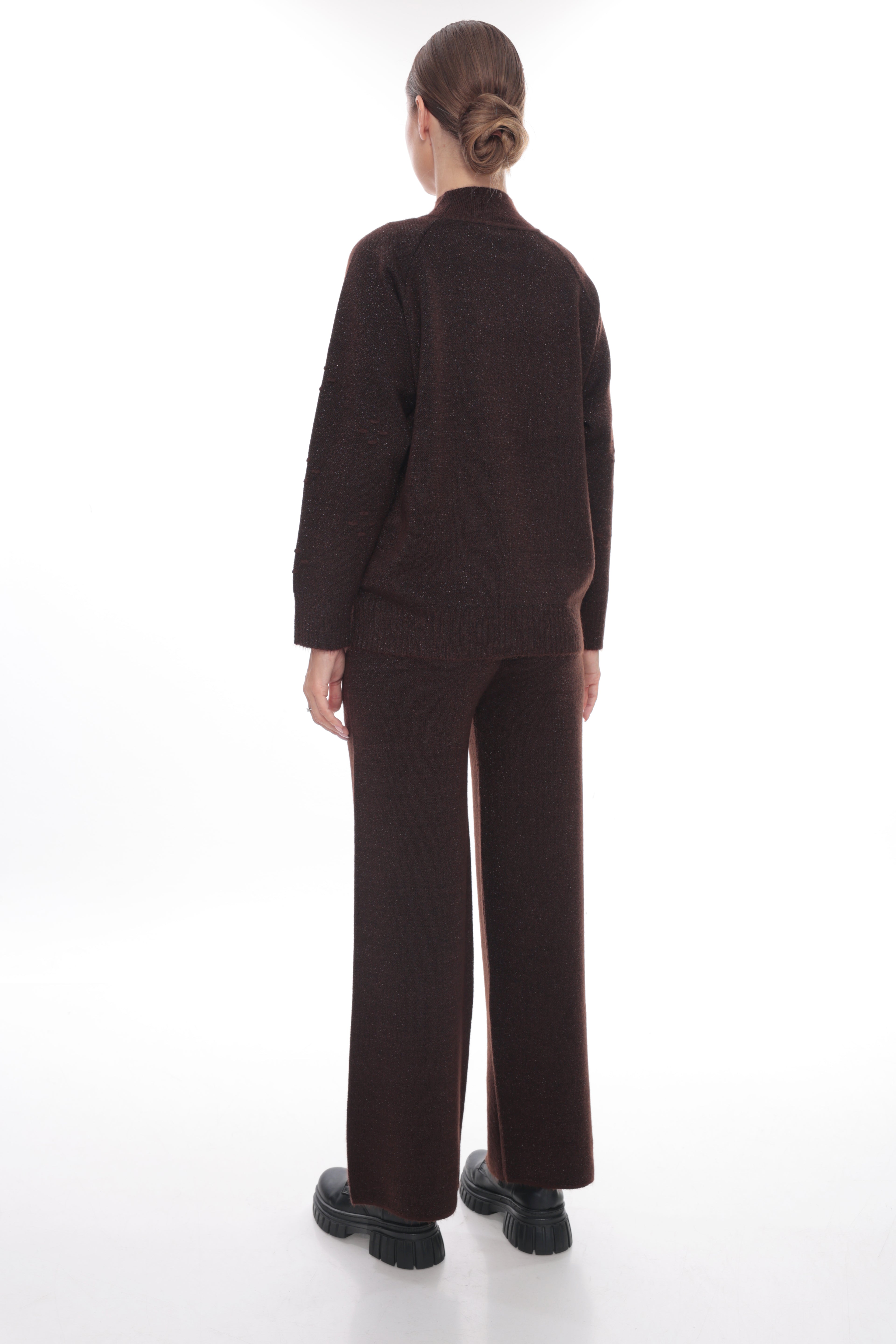 A model viewed from the back wearing a dark brown knit matching set consisting of a mock-neck long-sleeve top and wide-leg trousers, paired with black platform shoes on a white studio background.