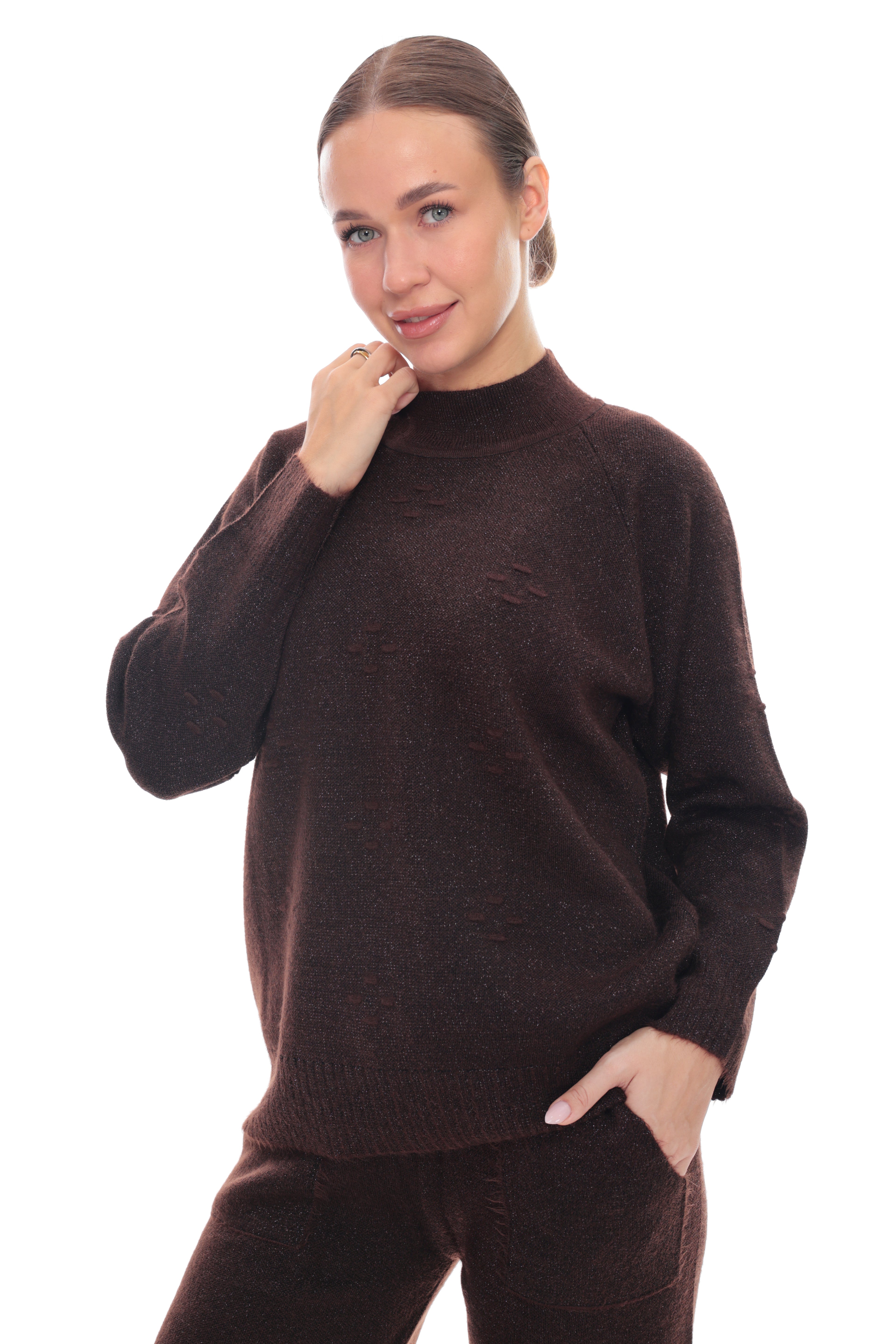 A woman modeling a dark brown knit mock neck sweater and matching brown pants against a solid white background.