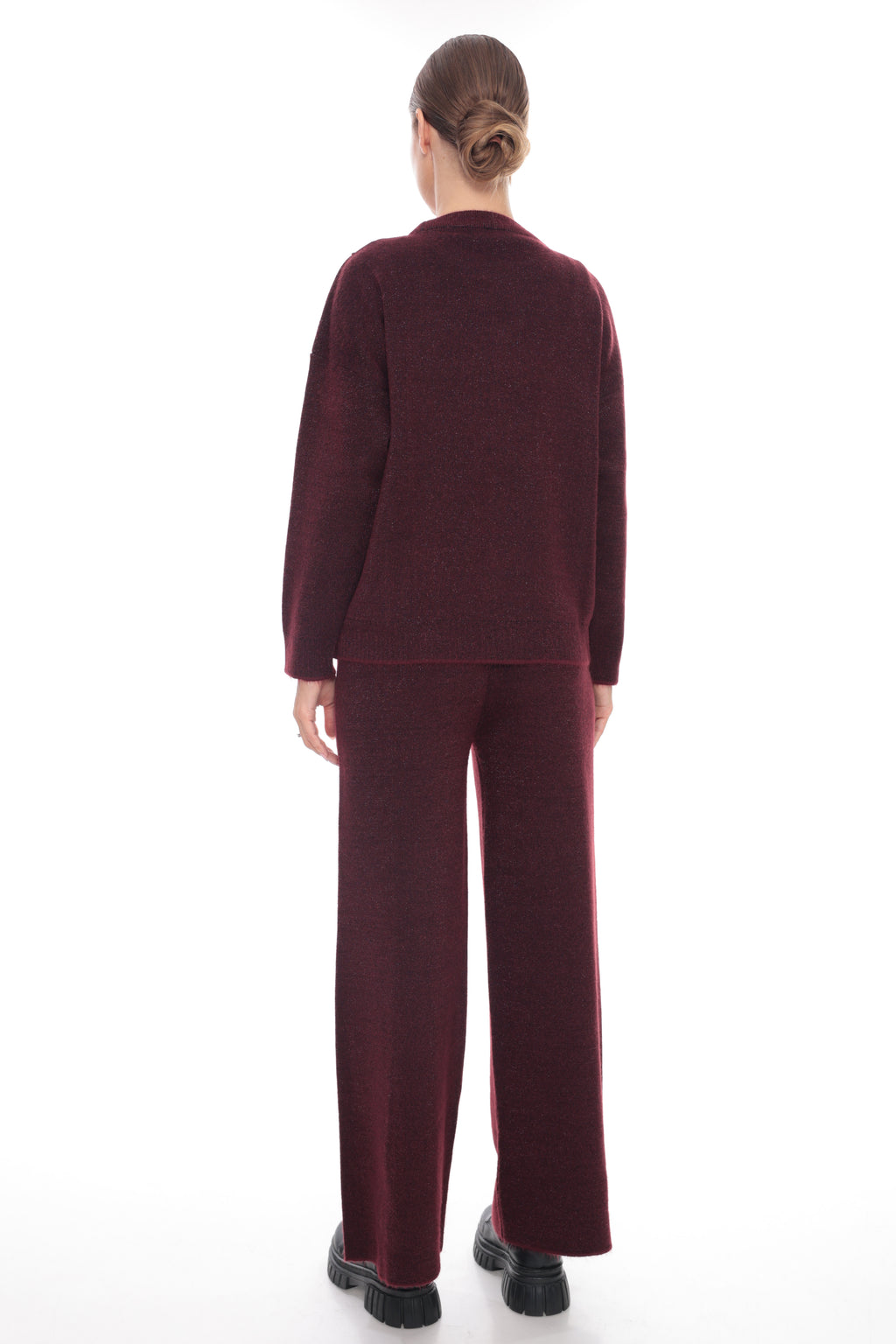 A model viewed from the back wearing a matching burgundy knit cardigan and wide-leg trousers set, paired with black platform shoes, against a solid white background.
