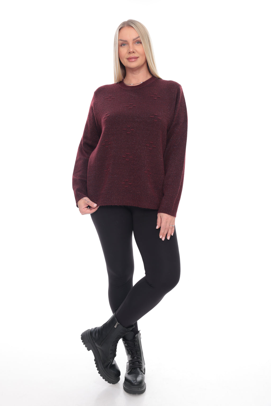 A woman modeling a maroon crewneck knit sweater, black leggings, and black combat boots against a plain white background.