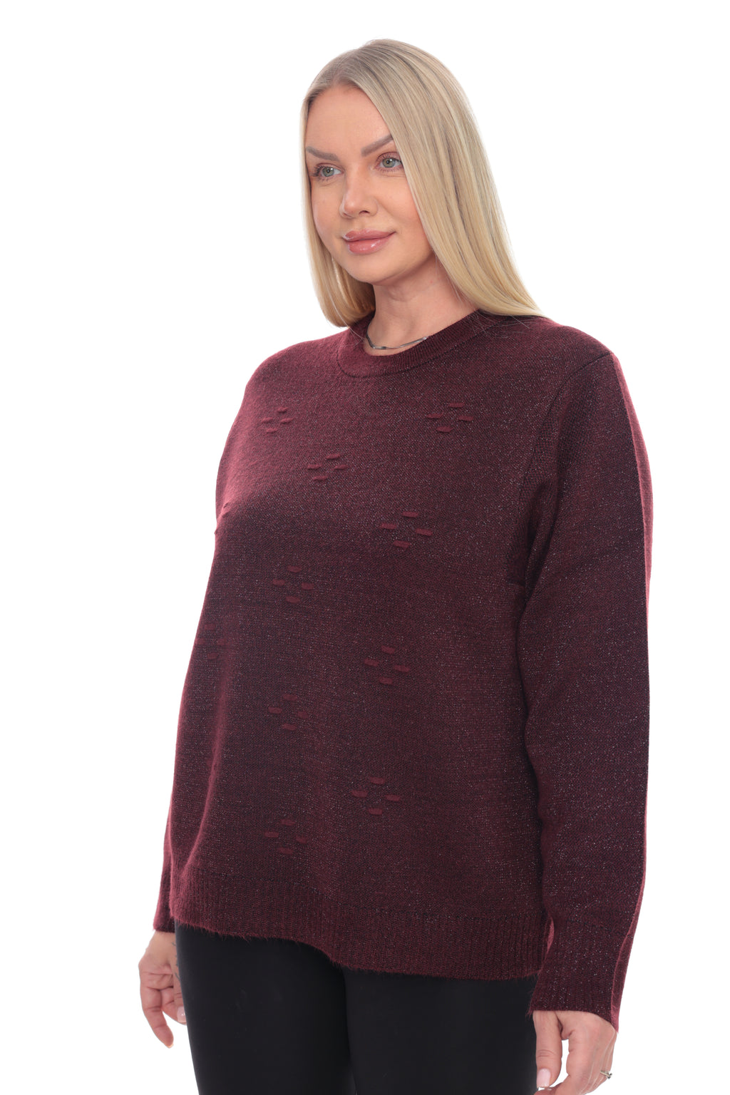 A blonde woman wearing a dark burgundy knit sweater with textured knit details, paired with black pants, against a plain white background.