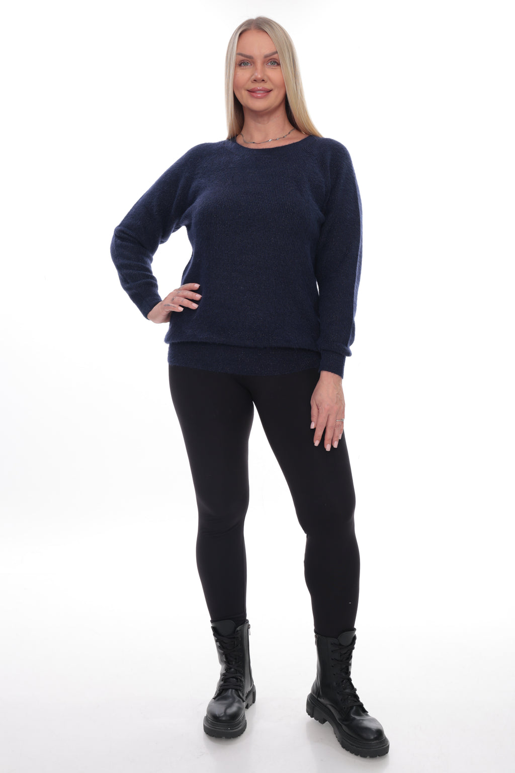 A woman modeling a dark navy blue crewneck sweater, paired with black leggings and black combat boots, against a plain white studio background.