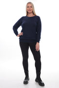 A woman modeling a dark navy blue crewneck sweater, paired with black leggings and black combat boots, against a plain white studio background.