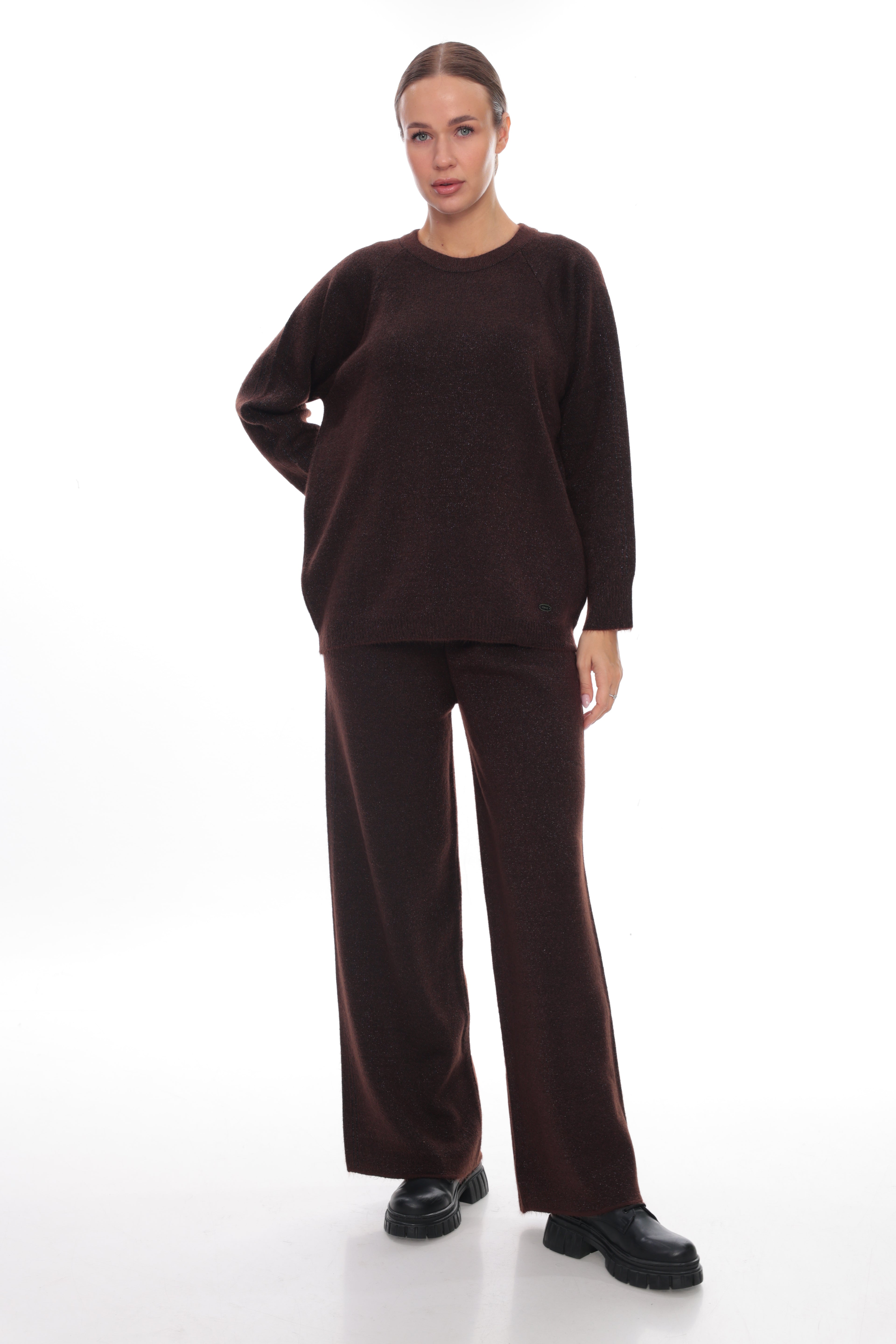 A woman modeling a dark brown knit sweater and matching wide-leg trousers against a plain white studio background.