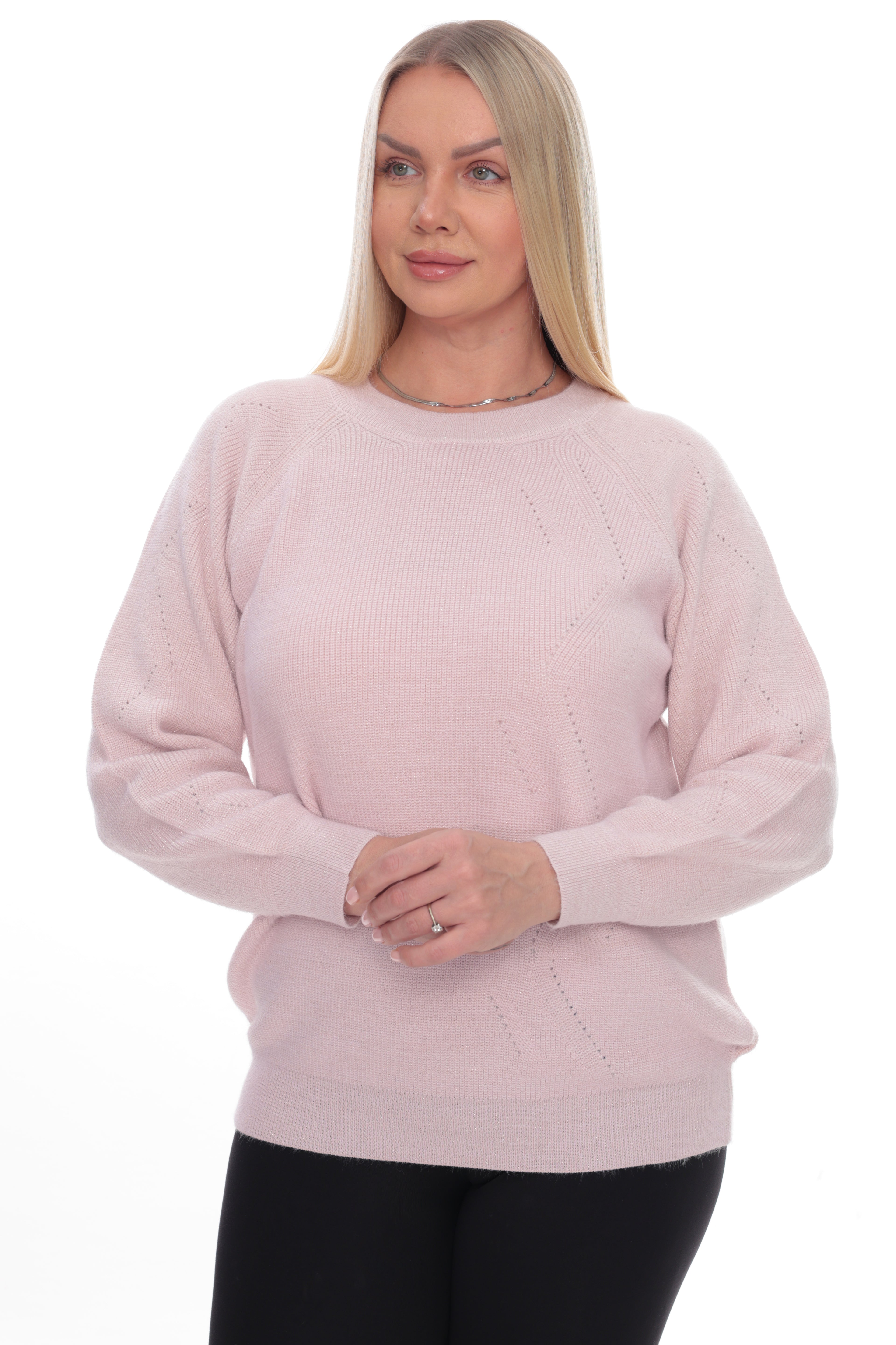 A blonde woman wearing a light pink long-sleeve knit sweater with textured knit details, paired with black pants, against a plain white background.