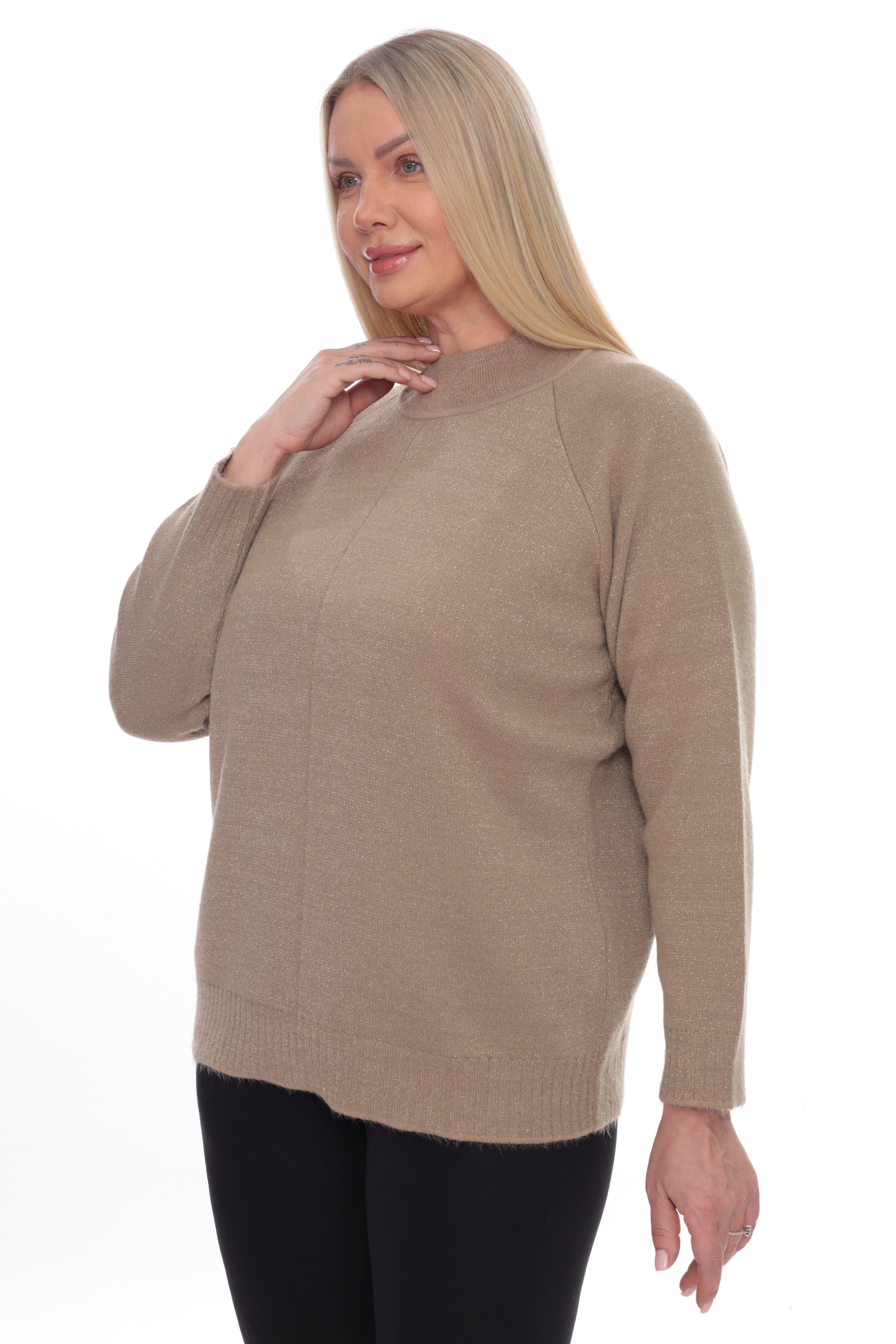 A woman modeling a light brown knit sweater with a mock neck and raglan sleeves, paired with black pants, against a plain white background.