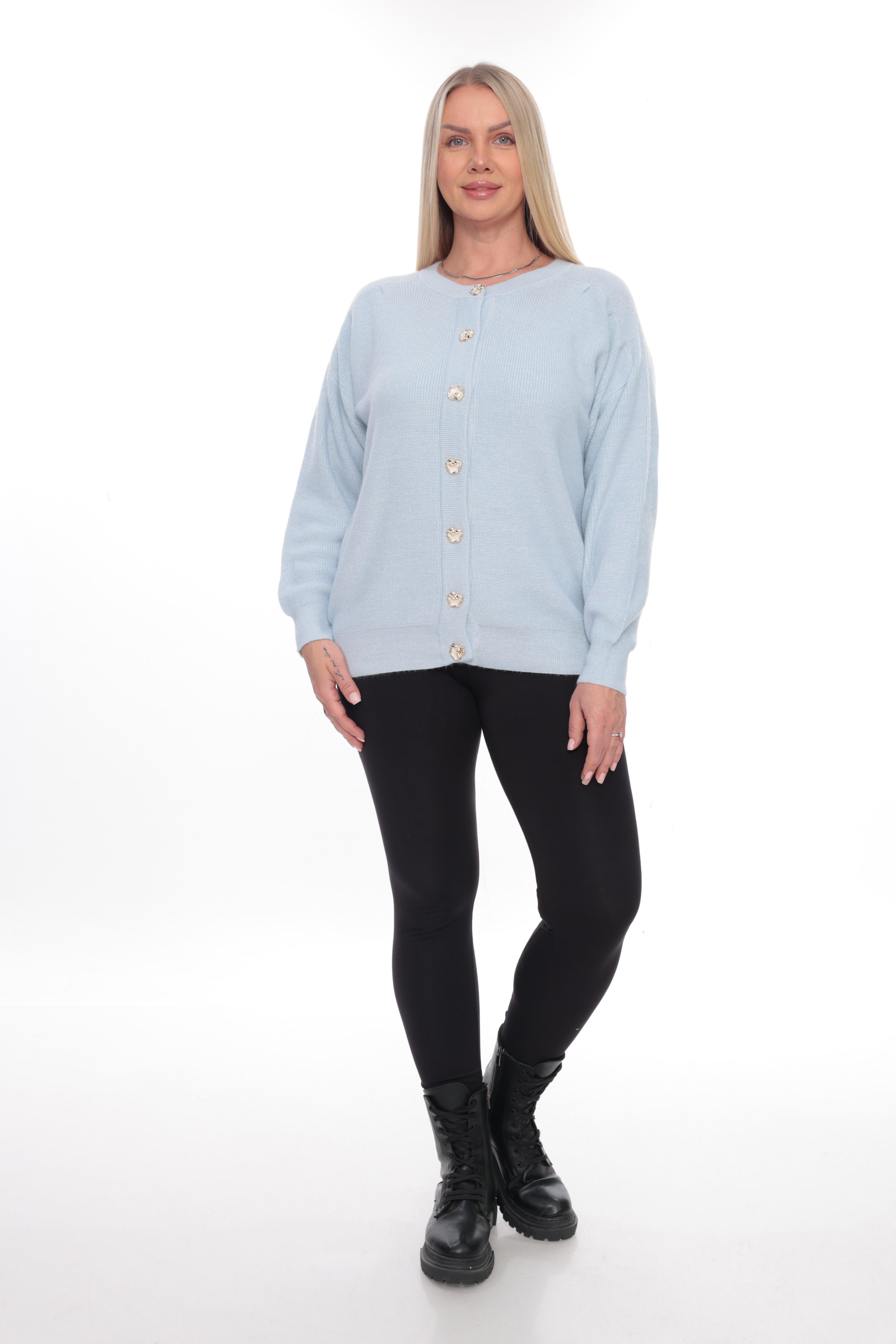 A woman modeling a light blue long-sleeve button-up cardigan with gold buttons, paired with black leggings and black boots, against a plain white studio background.