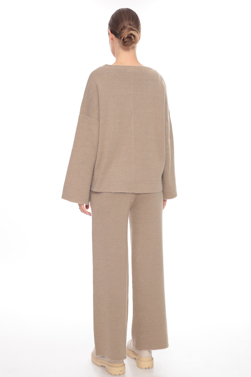 A model viewed from the back wearing a matching beige knit two-piece set consisting of a wide-sleeve top and wide-leg trousers, paired with beige platform shoes on a white background.