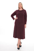 A woman modeling a long-sleeve knit midi dress in a deep burgundy color, paired with black pointed-toe heels, against a plain white studio background.