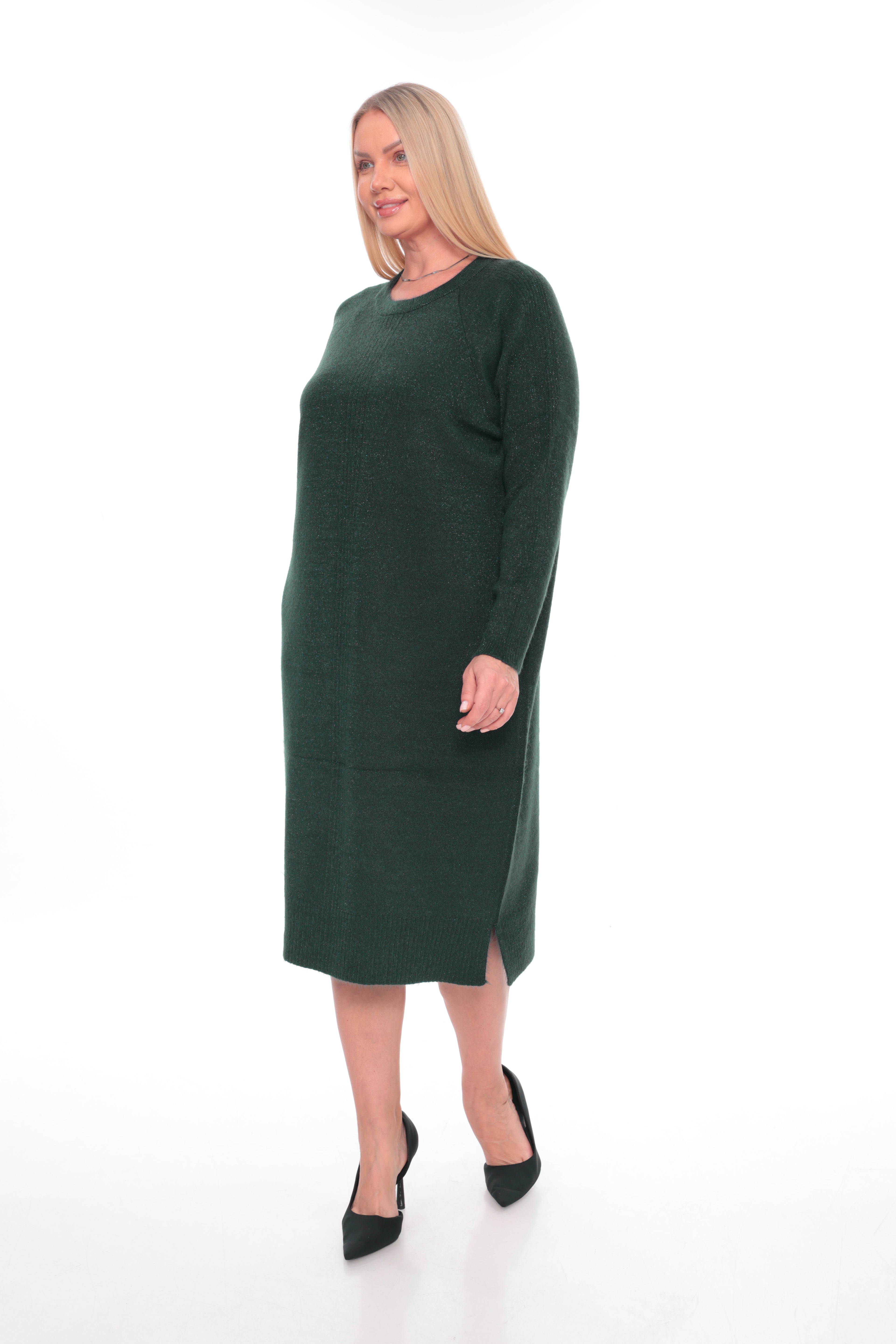 A woman modeling a dark forest green long-sleeve knit midi dress with a crew neck and side slit, paired with black pointed-toe heels, against a plain white studio background.