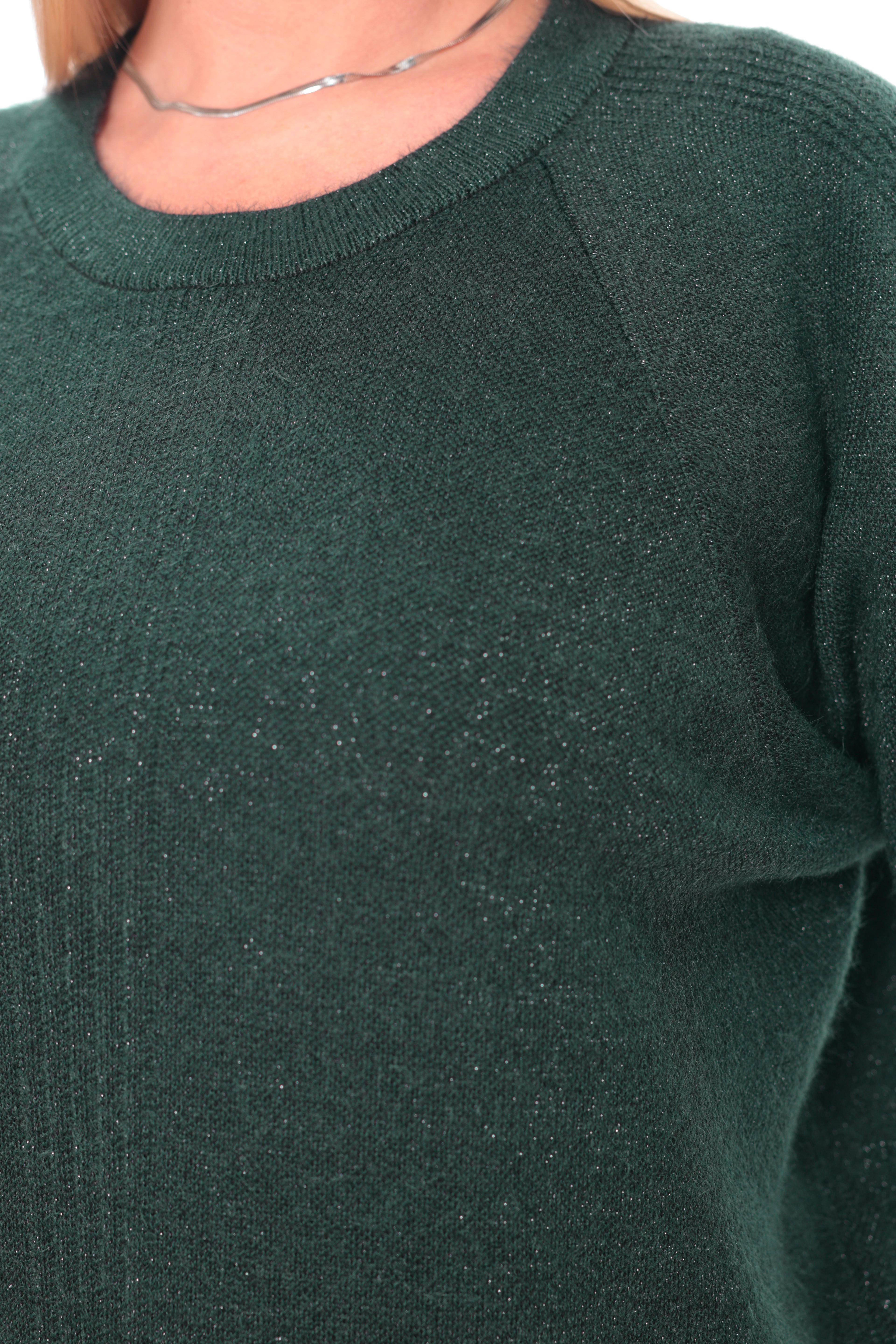 Close-up of a person wearing a dark forest green knit sweater with subtle shimmering flecks, paired with a thin silver necklace.