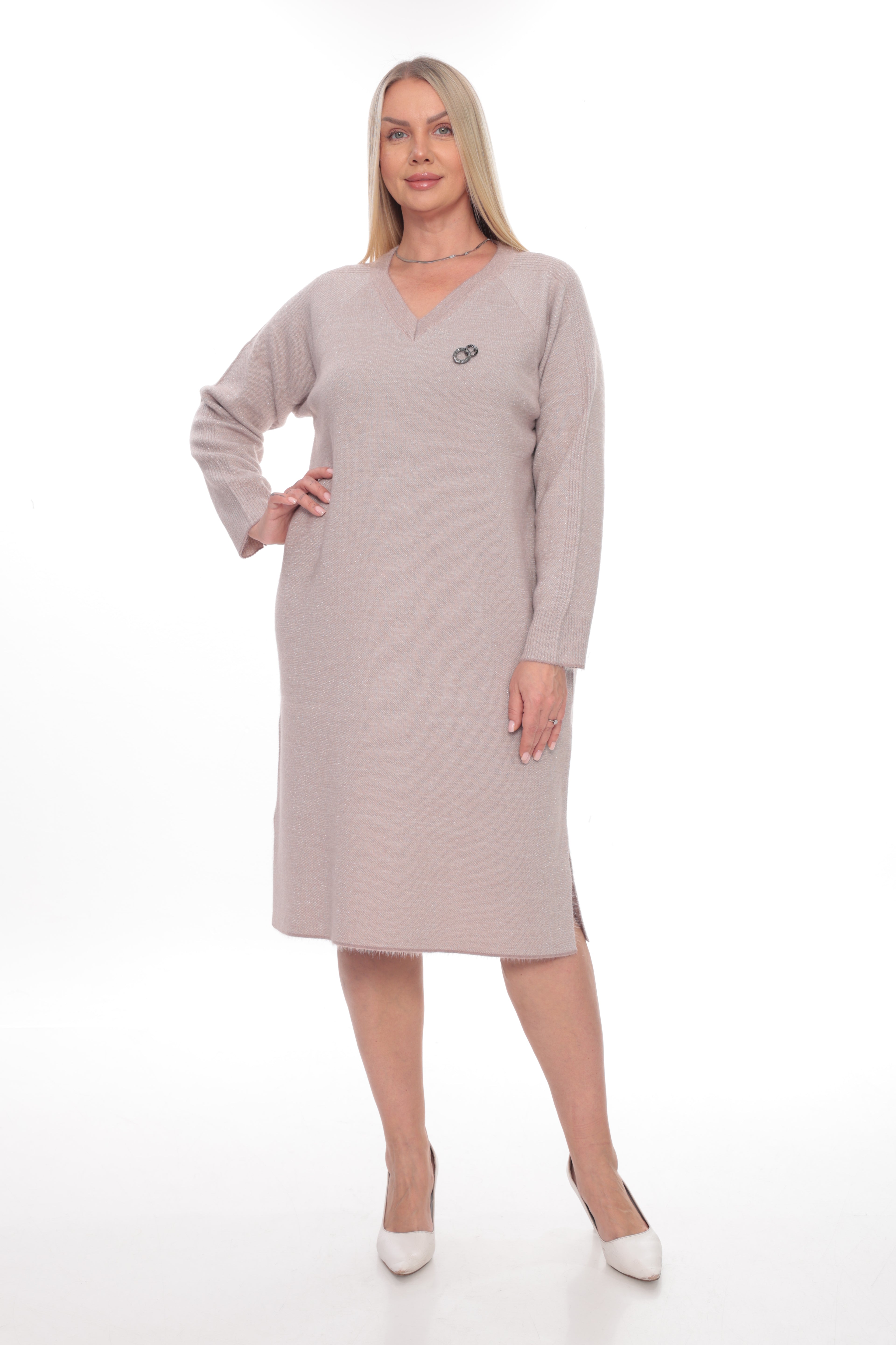 A woman modeling a long-sleeve, knee-length V-neck dress in a light taupe-beige color, featuring a small circular logo on the left chest, set against a plain white studio background.
