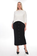 A woman modeling a black midi skirt with front buttons and textured pocket details, paired with a white long-sleeve top and black pointed heels, against a white studio background.