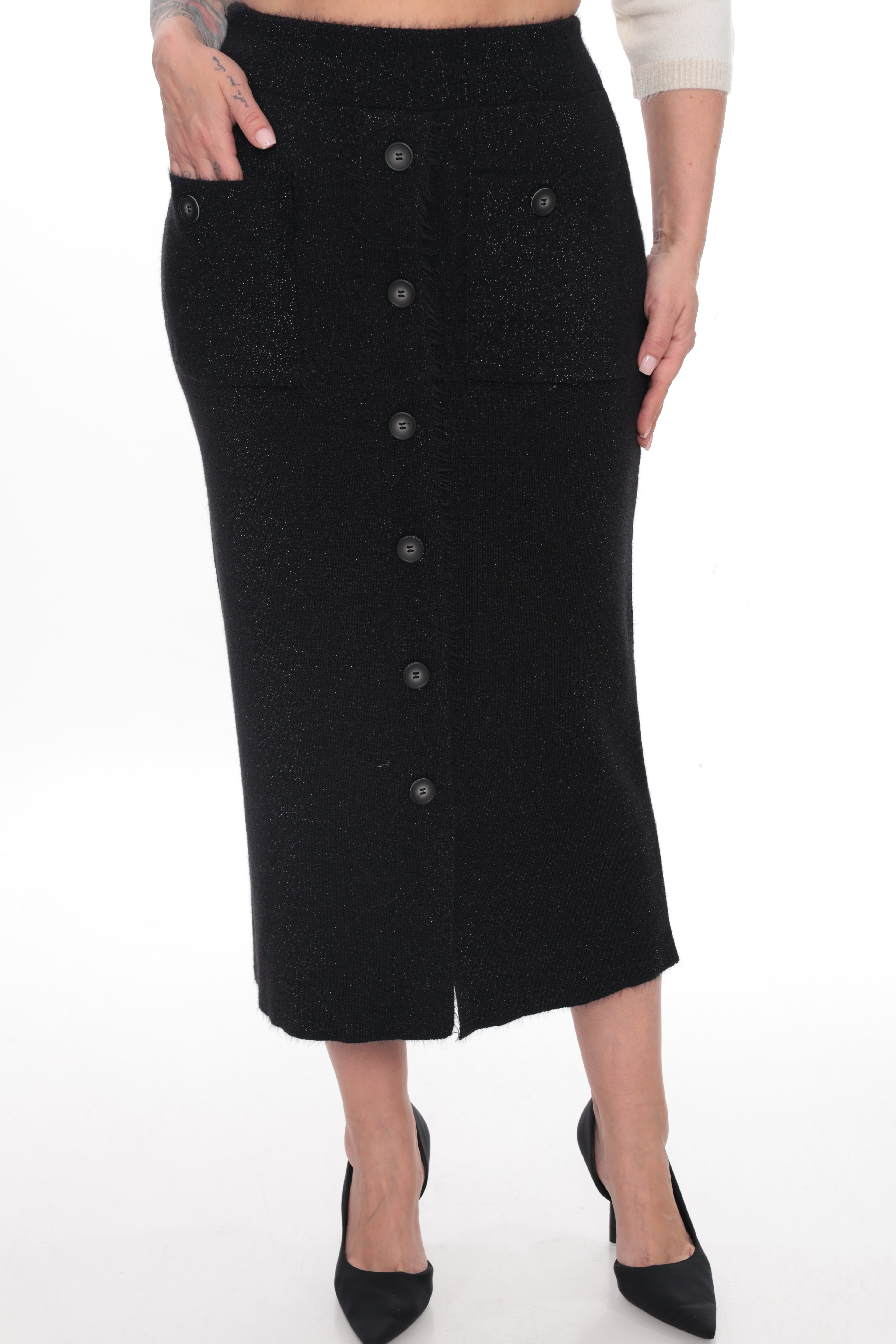 A black knit midi skirt with a front button closure and side pockets, shown on a model wearing black pointed-toe heels against a white studio background.