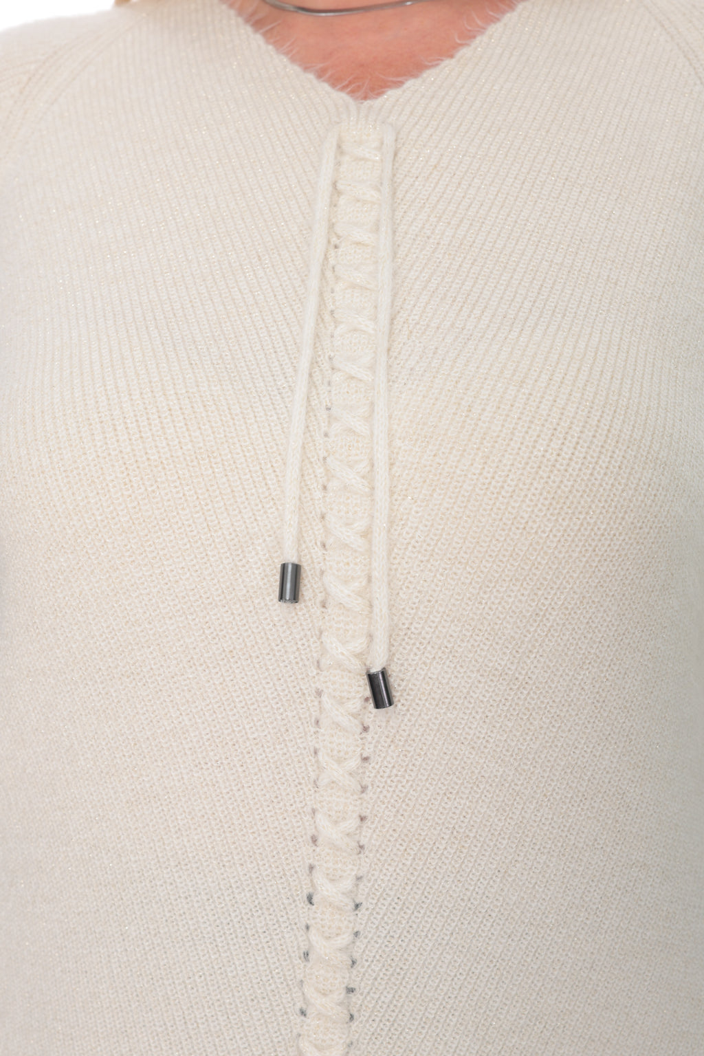Close-up of a cream-colored knit sweater featuring a decorative braided button placket with two small black metal snap accents.
