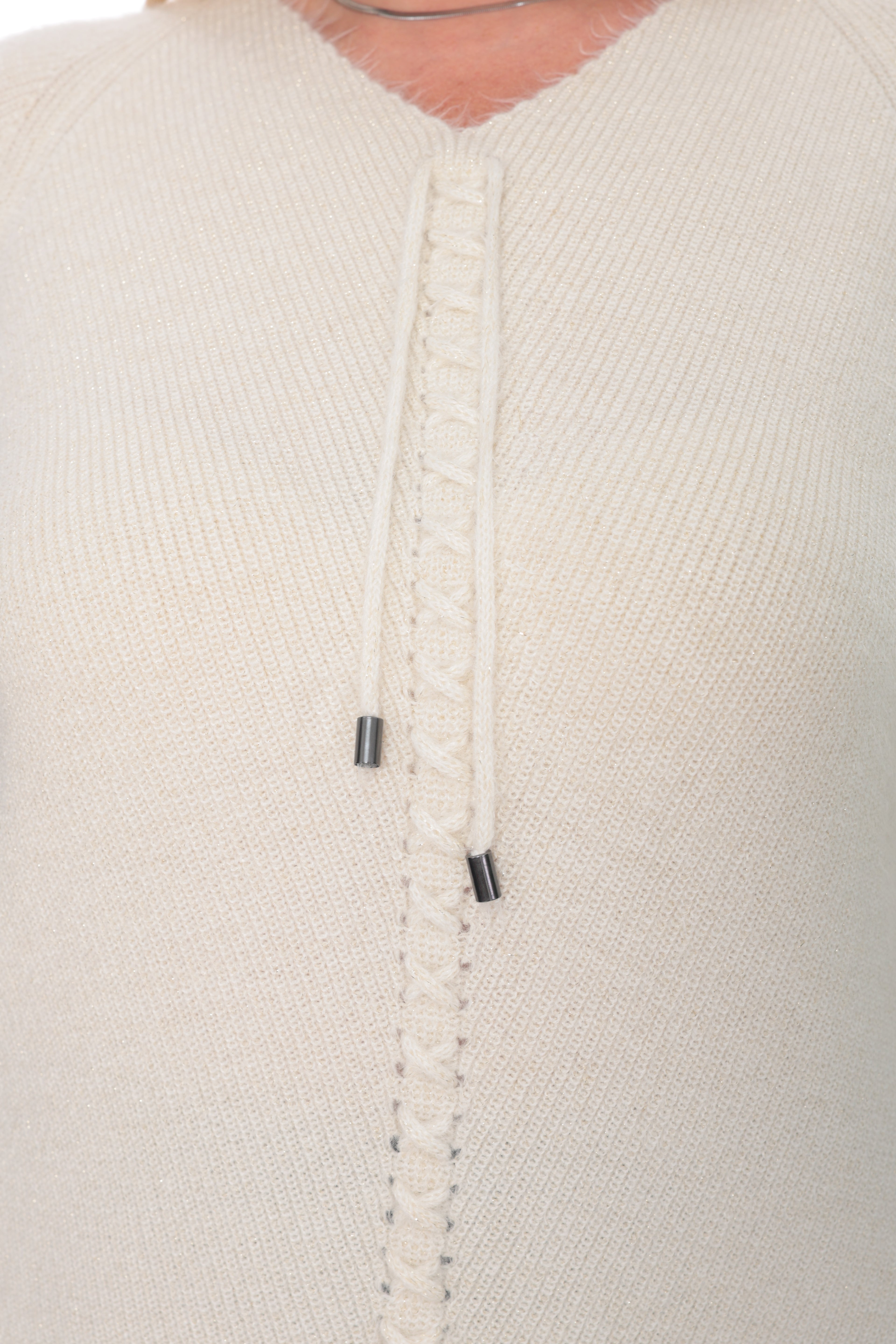 Close-up of a cream-colored knit sweater featuring a decorative braided button placket with two small black metal snap accents.